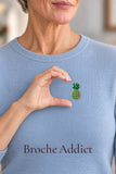 Broche ananas en strass verts et dorés portée sur un pull bleu clair