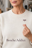 Broche Libellule Nuit Étoilée portée sur un pull blanc avec un geste de cœur coréen