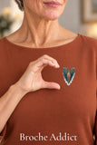 Broche Ailes d’Ange bleue portée sur une blouse rouille avec un geste de demi-cœur
